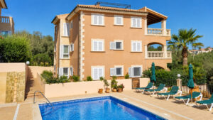 Außenansicht auf das Mehrfamilienhaus in Cala Mandia mit dem Gemeinschaftspool und der Terrasse im Vordergrund